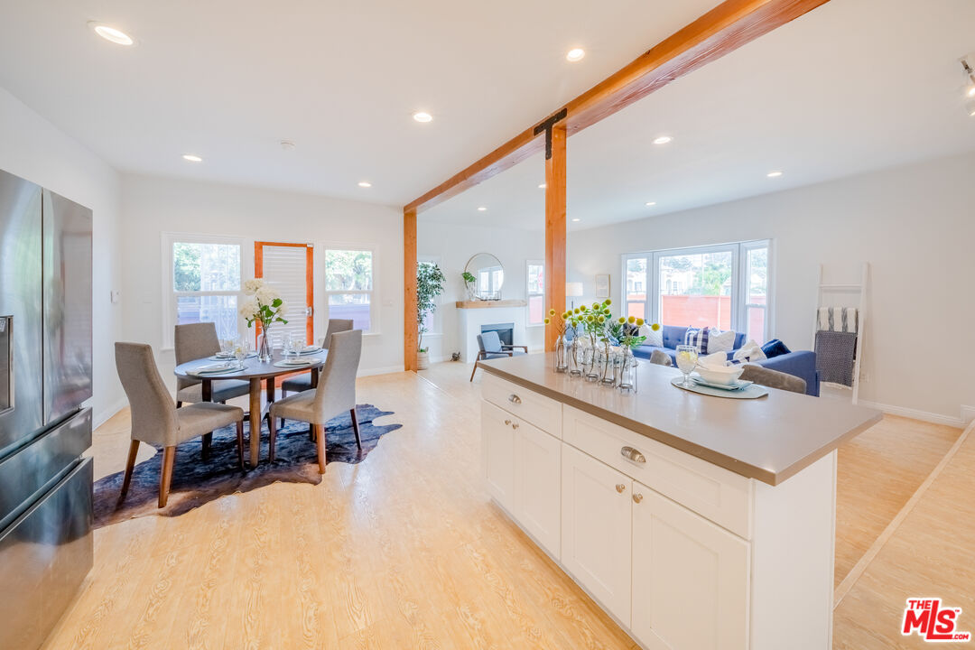 1251 South Muirfield Road Los Angeles, CA 90019 - Photo 4 of 24 a large white dining room with stainless steel appliances kitchen island a table and chairs in it