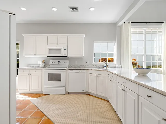a white kitchen with granite countertop white cabinets and white appliances