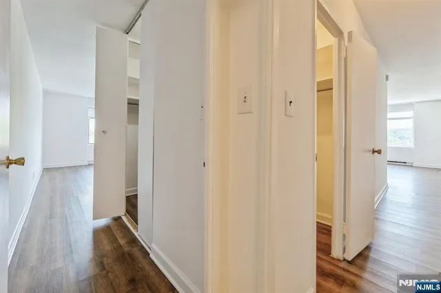 a view of an empty room with wooden floor and closet