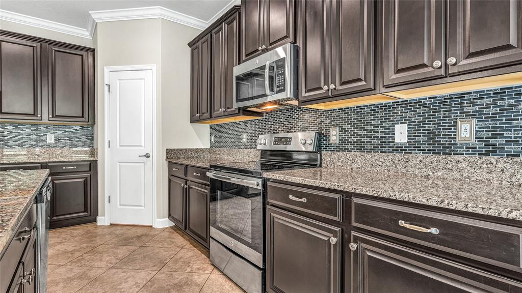 1695 Ludington Avenue Wesley Chapel, FL 33543 - Photo 18 of 65 a kitchen with stainless steel appliances granite countertop a sink stove and refrigerator