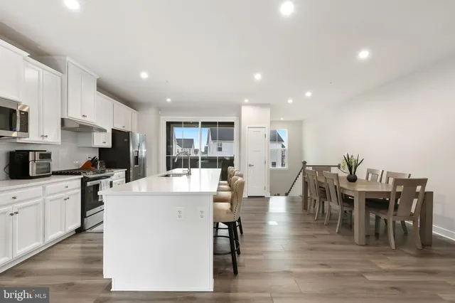 a kitchen with stainless steel appliances a table chairs refrigerator and microwave