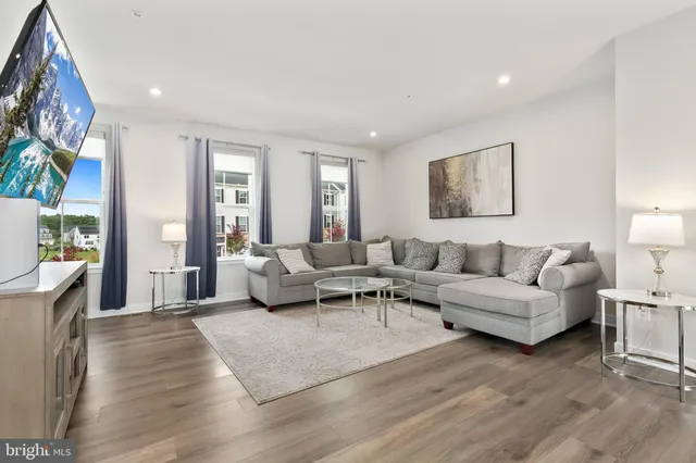 a living room with furniture flat screen tv and a large window