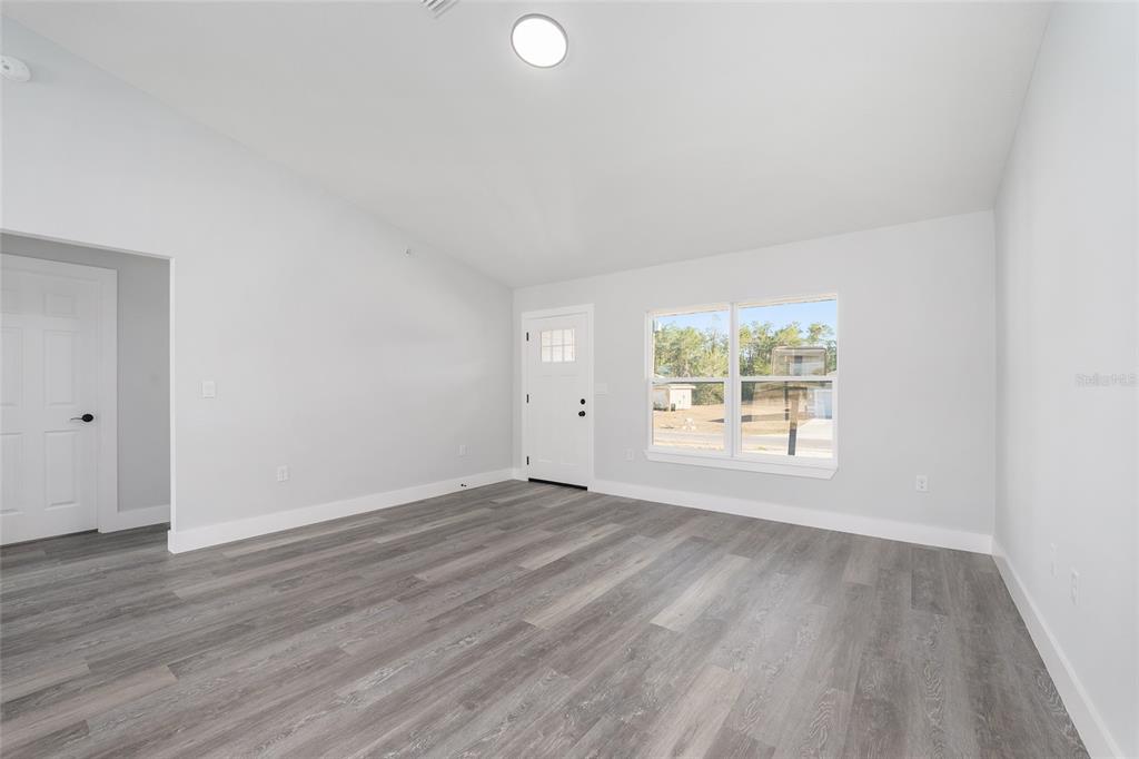 3244 Southeast 147th Lane Summerfield, FL 34491 - Photo 2 of 25 an empty room with wooden floor and windows