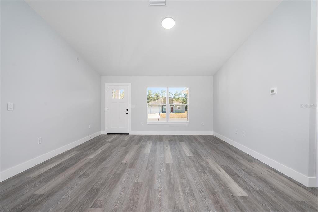 3244 Southeast 147th Lane Summerfield, FL 34491 - Photo 3 of 25 an empty room with wooden floor and windows