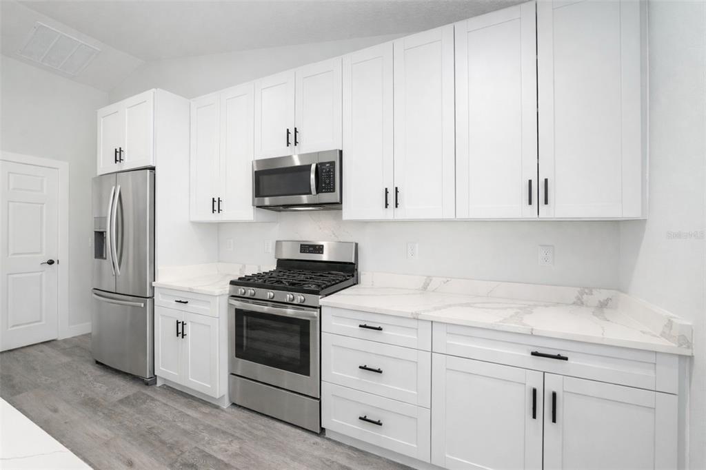 3244 Southeast 147th Lane Summerfield, FL 34491 - Photo 5 of 25 a kitchen with white cabinets and white appliances