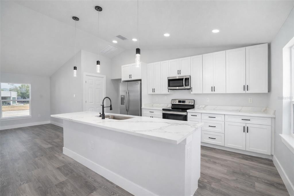 3244 Southeast 147th Lane Summerfield, FL 34491 - Photo 6 of 25 a kitchen with granite countertop a sink stove and microwave