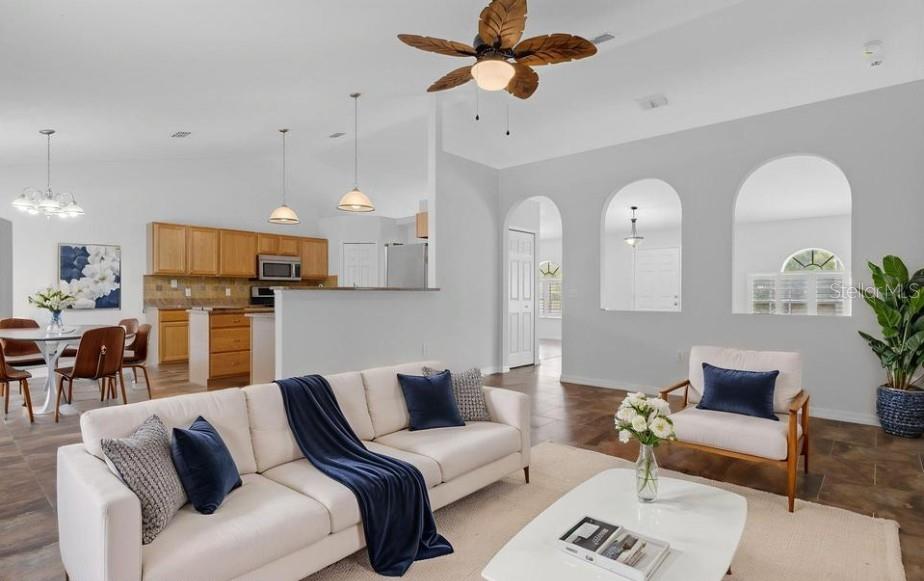 12411 Convent Garden Road Brooksville, FL 34613 - Photo 7 of 49 a living room with furniture kitchen view and a chandelier