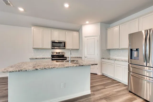 a kitchen with stainless steel appliances granite countertop a refrigerator stove microwave and sink