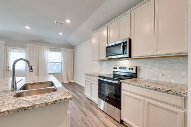 a kitchen with granite countertop white cabinets and appliances