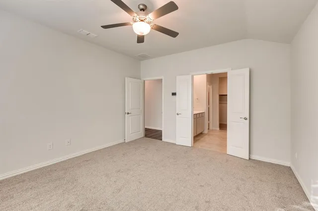 an empty room with closet and a ceiling fan