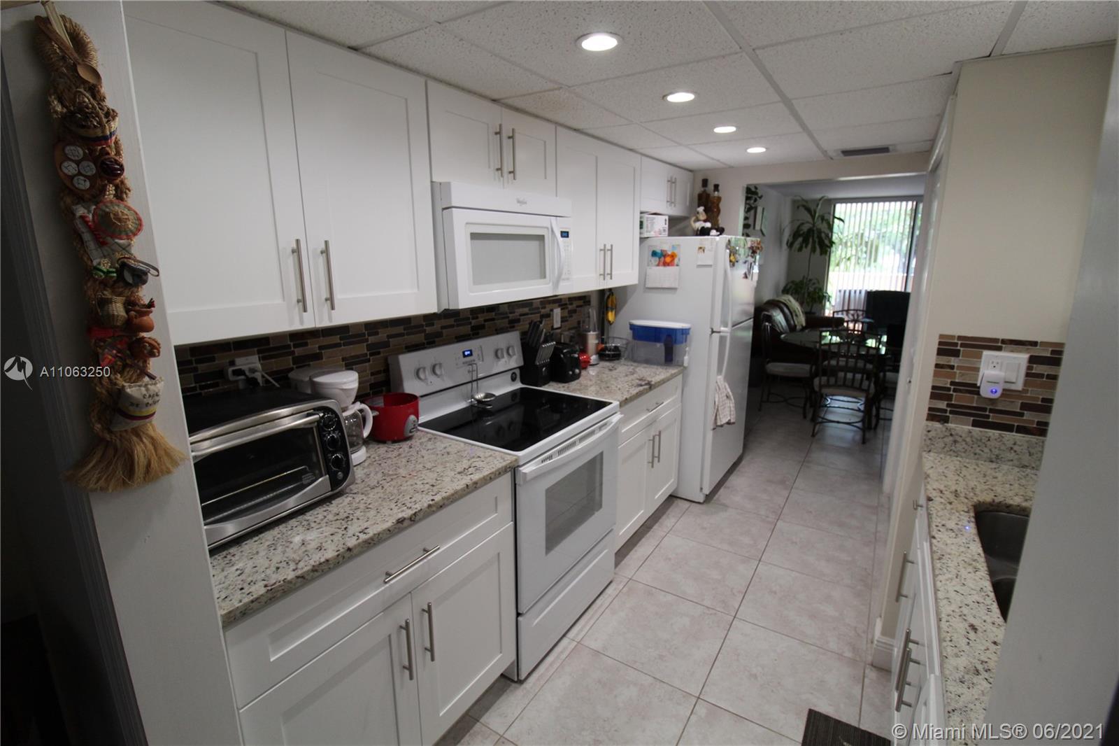 7451 Northwest 16th Street, Unit 210 Plantation, FL 33313 - Photo 5 of 16 a kitchen with white cabinets and appliances