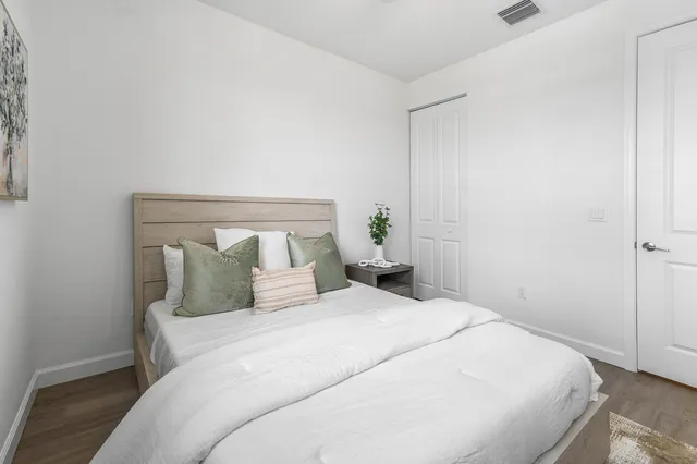 a bedroom with a large bed and wooden floor