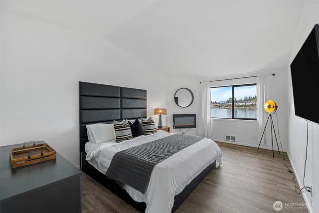 a spacious bedroom with a bed a couch and large window