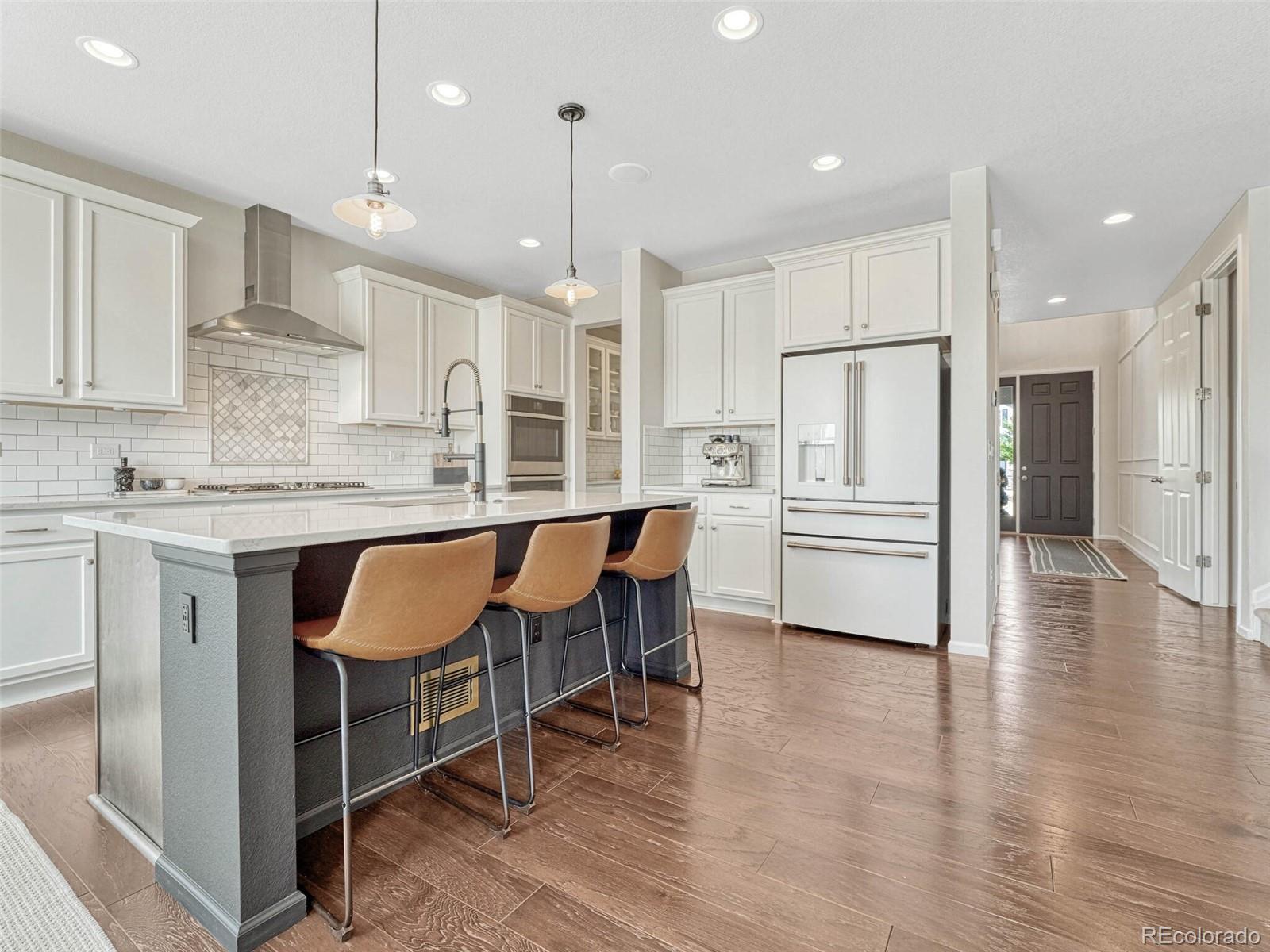 5921 Berry Ridge Wy. Castle Rock, CO 80104 - Photo 5 of 43 a kitchen with stainless steel appliances kitchen island granite countertop a table chairs refrigerator and sink