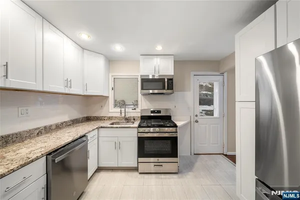 a kitchen with stainless steel appliances granite countertop a stove a refrigerator and a sink