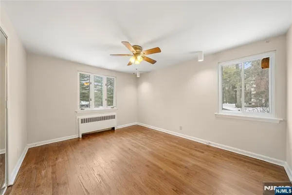 a view of an empty room with a window and wooden floor