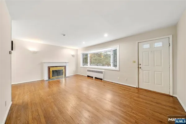 a view of empty room with wooden floor and fireplace