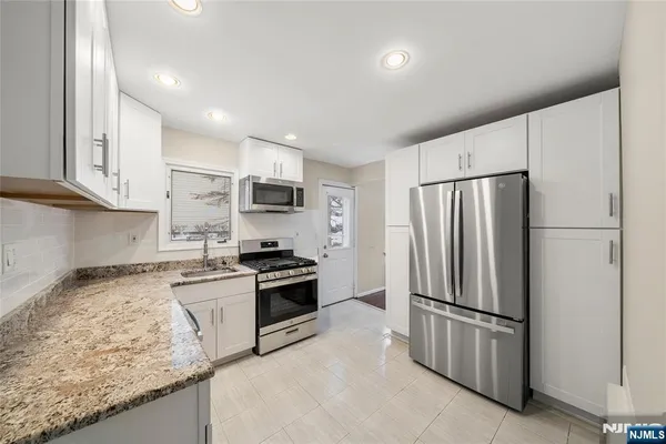 a kitchen with granite countertop stainless steel appliances and refrigerator