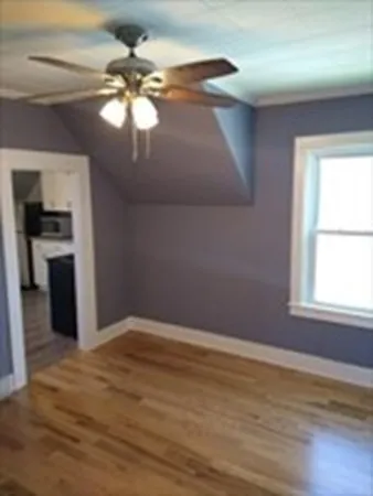 a view of an empty room with window and wooden floor