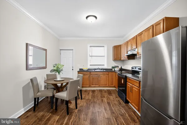 a kitchen with stainless steel appliances granite countertop a stove a refrigerator a sink a dining table and chairs with wooden floor