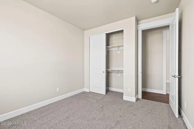 a view of an empty room with closet and a bathroom