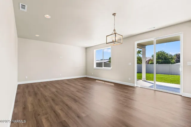 a view of an empty room with window and wooden floor