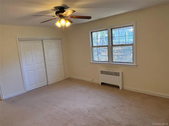 an empty room with chandelier fan and windows
