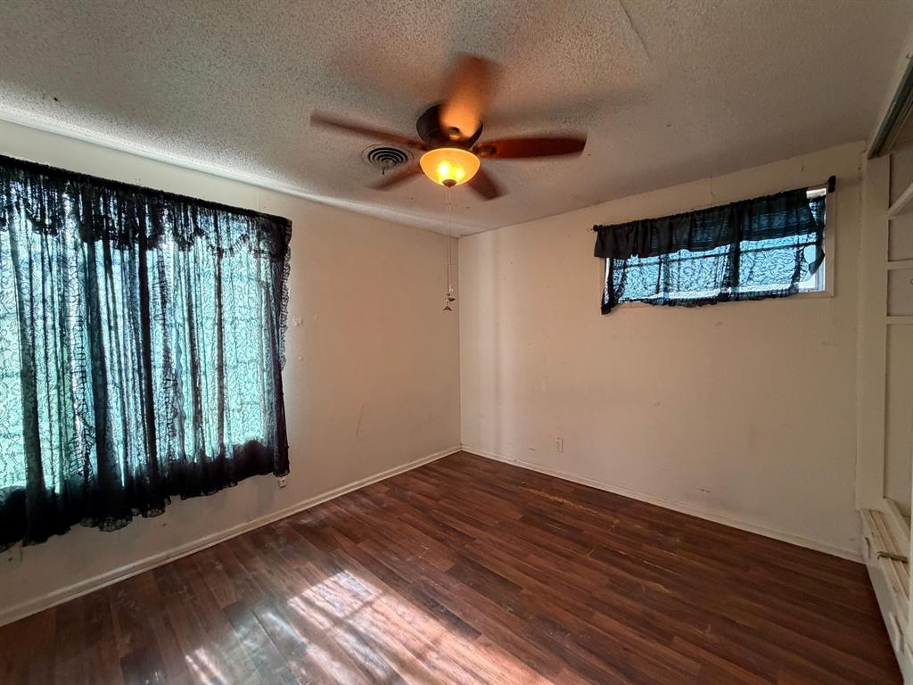 1225 Coit Street Denton, TX 76201 - Photo 12 of 13 an empty room with wooden floor chandelier fan and windows