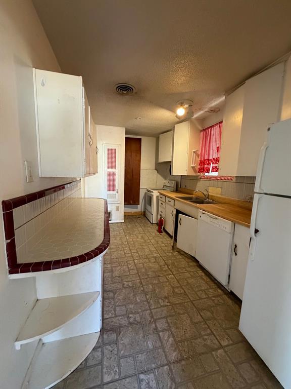 1225 Coit Street Denton, TX 76201 - Photo 6 of 13 a kitchen with a sink a stove a refrigerator and a cabinets