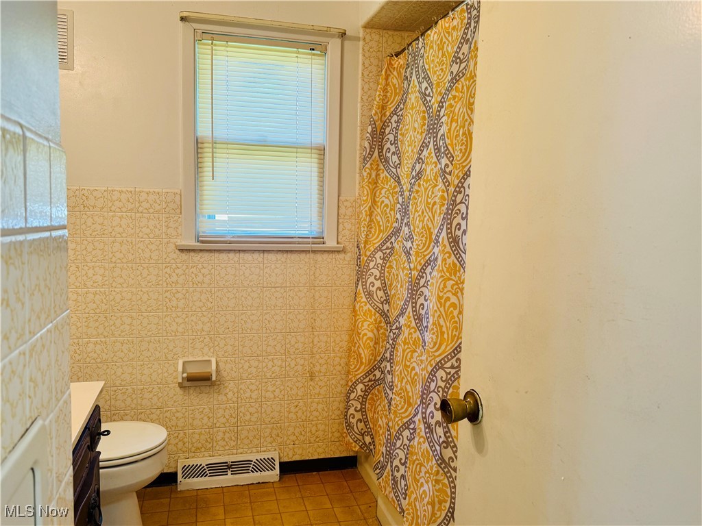 25911 Tryon Road Bedford, OH 44146 - Photo 19 of 49 Full bath featuring visible vents, tile patterned flooring, toilet, tile walls, and a wainscoted wall