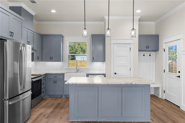 a large kitchen with granite countertop a sink a counter space stainless steel appliances and cabinets