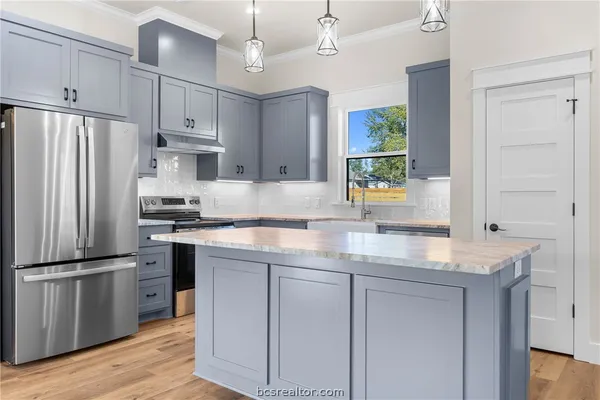 a kitchen with kitchen island granite countertop a sink cabinets and stainless steel appliances