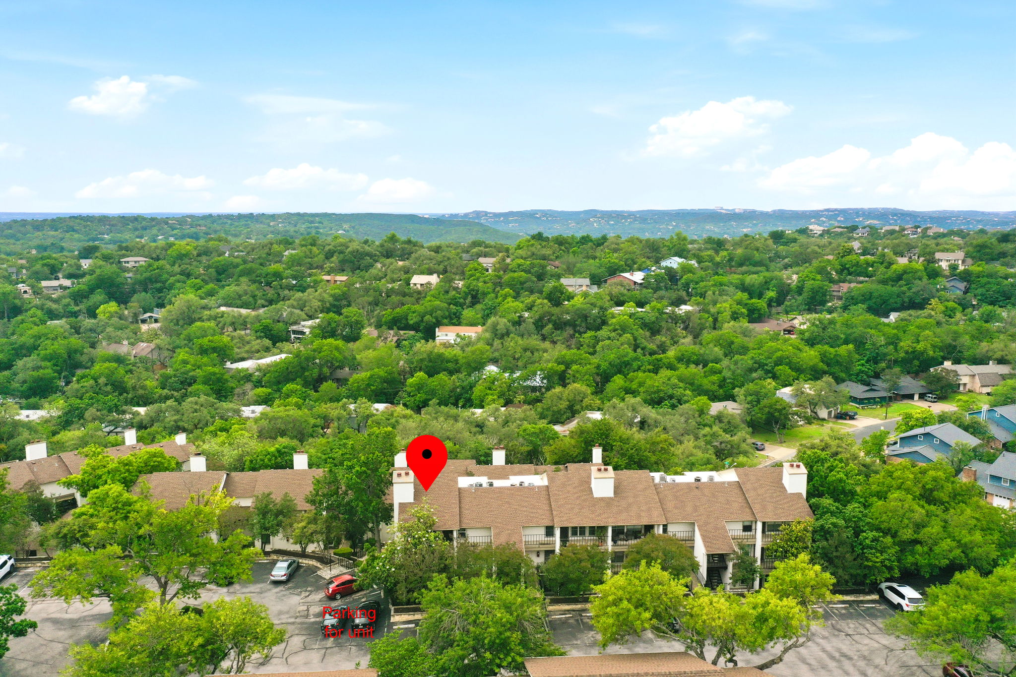 6910 Hart Lane, Unit 912 Austin, TX 78731 - Photo 31 of 36 Multi-story residential buildings with brown shingle roofing and white chimneys, set among abundant mature trees