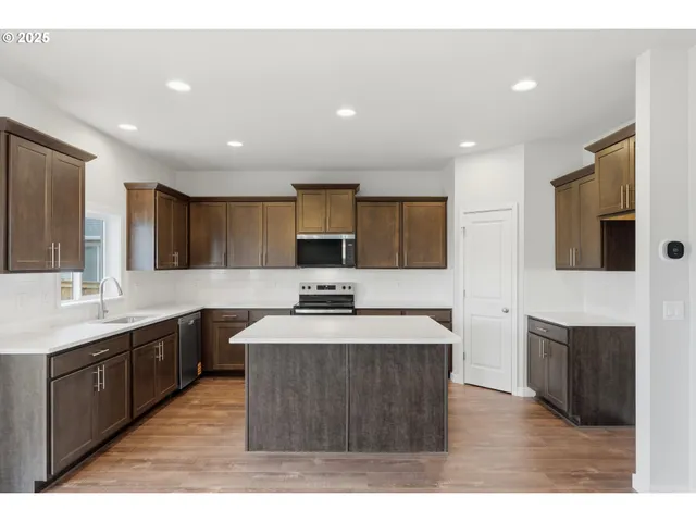 a large kitchen with stainless steel appliances kitchen island granite countertop a large counter top and a sink