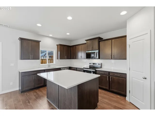 a kitchen with stainless steel appliances a sink a stove a refrigerator cabinets and a window