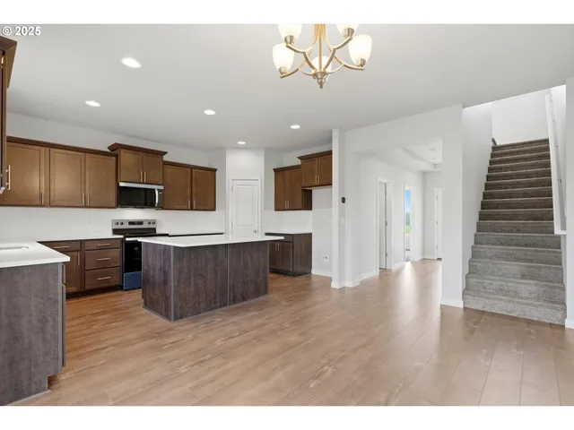 a kitchen with stainless steel appliances kitchen island wooden floors wooden cabinets and entryway