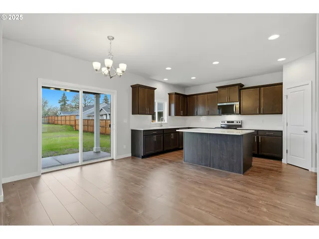 a large kitchen with stainless steel appliances kitchen island a large counter top a sink cabinets and wooden floor