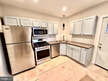 a kitchen with stainless steel appliances granite countertop a refrigerator a stove a sink and a microwave