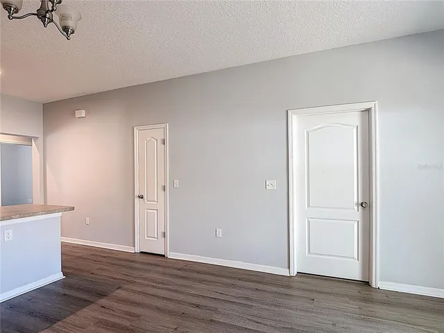 a view of an empty room with wooden floor and closet
