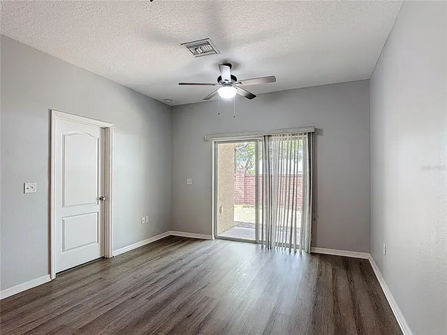 an empty room with wooden floor ceiling fan and windows
