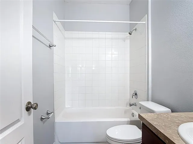 a bathroom with a granite countertop toilet sink and bathtub