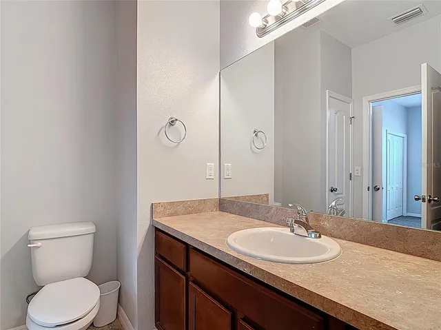 a bathroom with a granite countertop sink toilet and mirror