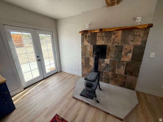 14183 High Mesa Loop Duchesne, UT 84021 - Photo 30 of 56 Unfurnished living room with light wood finished floors, french doors, a wood stove, and a textured ceiling
