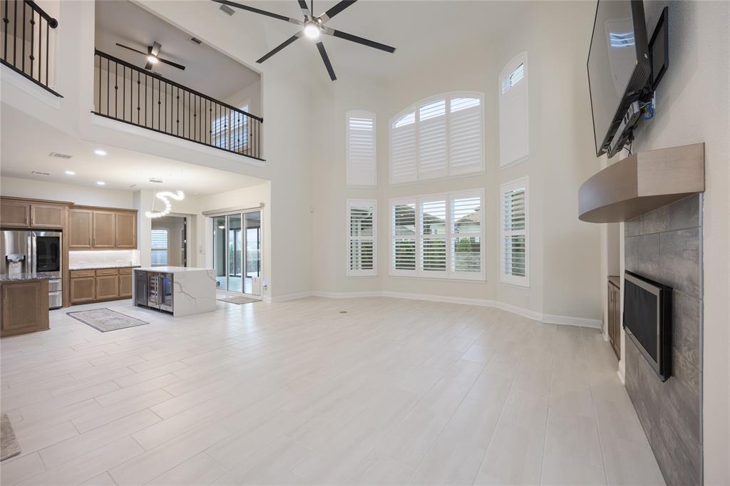918 Sydney Lane Allen, TX 75013 - Photo 7 of 40 Expansive living area featuring high ceilings, light-toned flooring, and large windows with white shutters