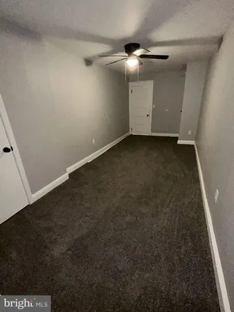 an empty room with a ceiling fan and carpet