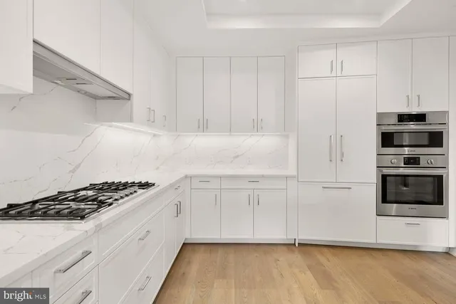 a kitchen with stainless steel appliances granite countertop a sink a oven a dining table and chairs