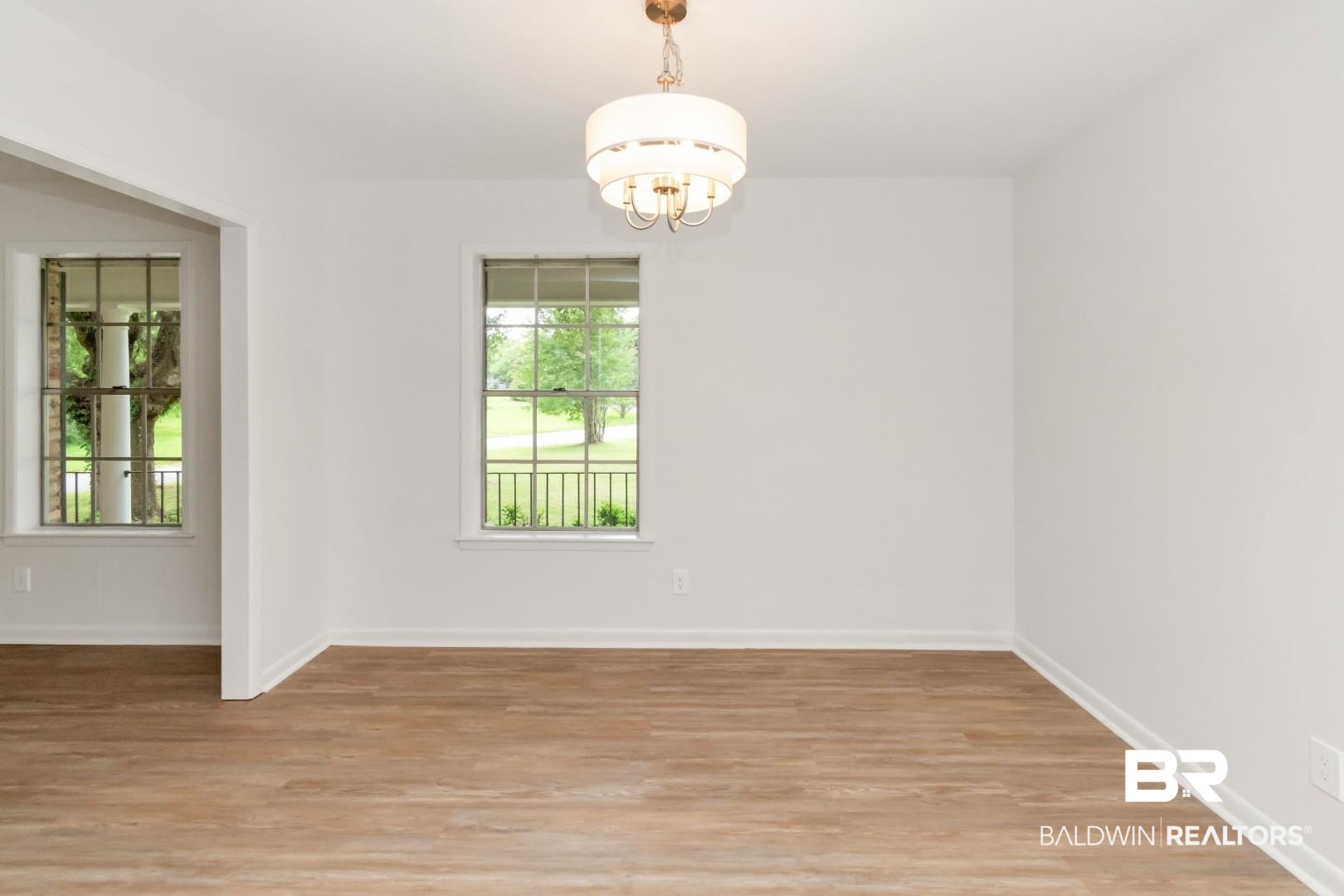 5217 Perin Road Mobile, AL 36693 - Photo 14 of 45 Spacious interior featuring wood-finish flooring, white walls, and a modern tiered chandelier