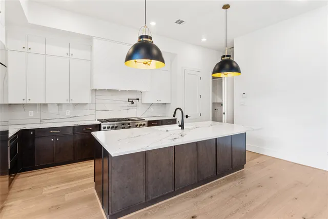 a kitchen with kitchen island granite countertop a sink a stove and a wooden floors