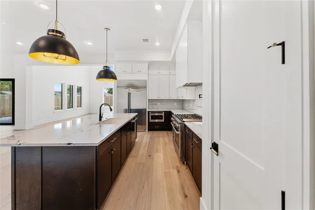 a kitchen with stainless steel appliances granite countertop a sink a stove and a wooden floors