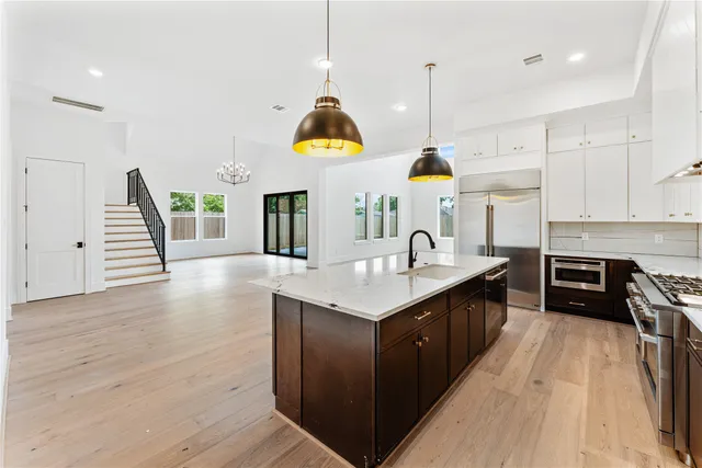 a kitchen with stainless steel appliances granite countertop a sink a stove and a wooden floors